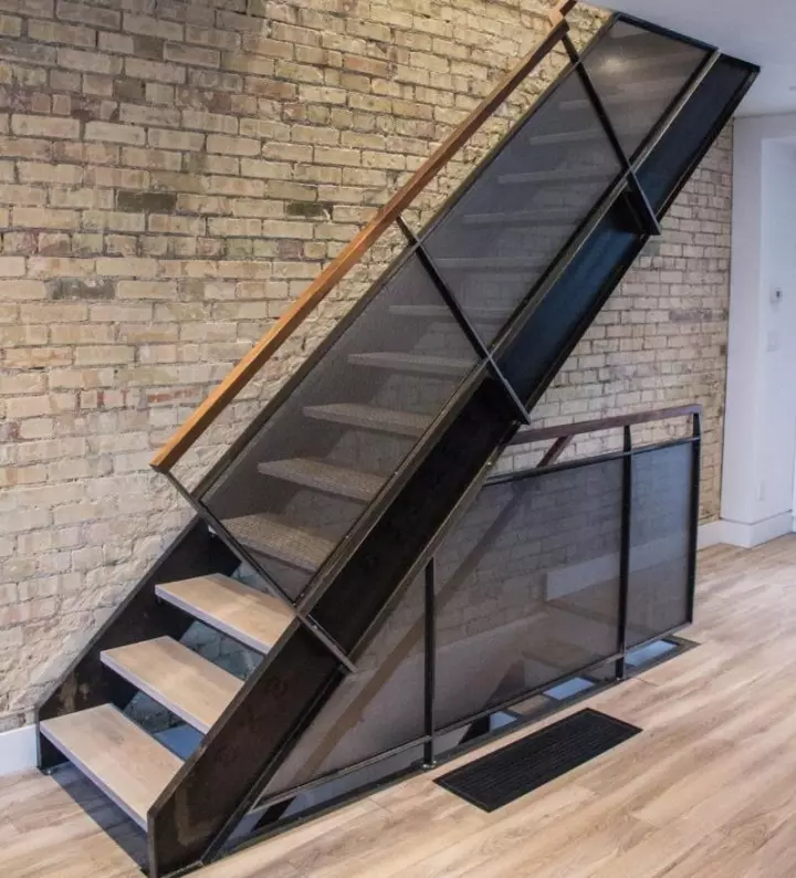 Modern steel and glass staircase against exposed brick
